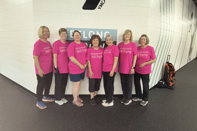 Group of people in pink shirts standing in front of a YMCA wall.