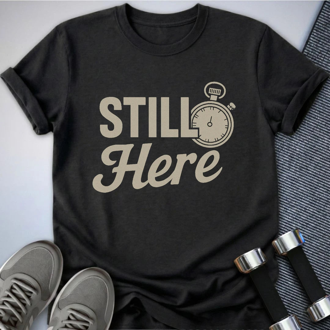 Printify T-Shirt Dark Grey Heather / S She's Still Here T-Shirt